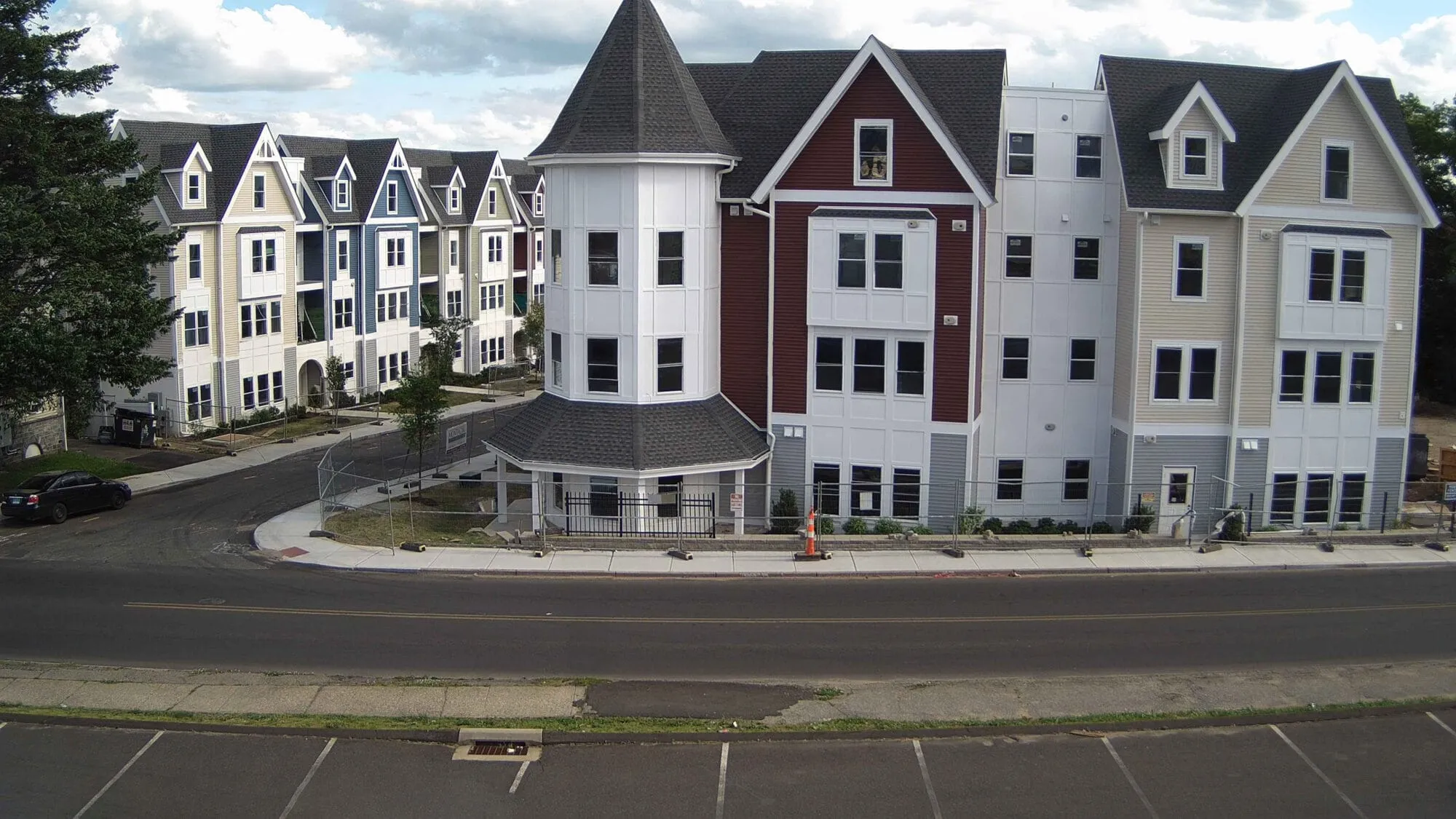 Linden Street Apartments in Waterbury after construction — a four-story building with a corner turret, red and white siding, and gabled rooflines along the street — cover image for the Montagno Construction website project