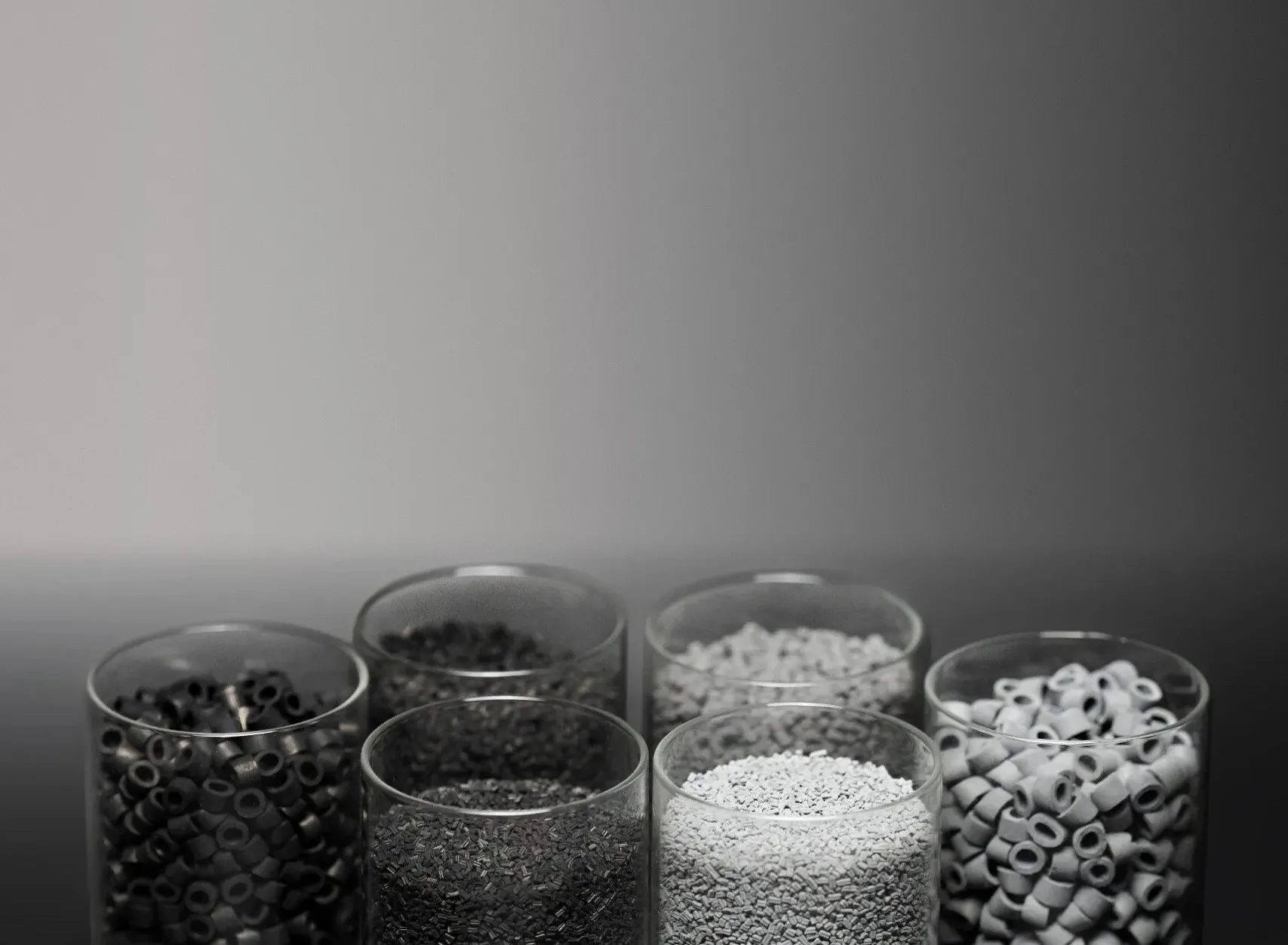 Glass beakers filled with black and white catalyst carrier pellets and rings against a gray background — cover image for the SiCat Catalyst website project