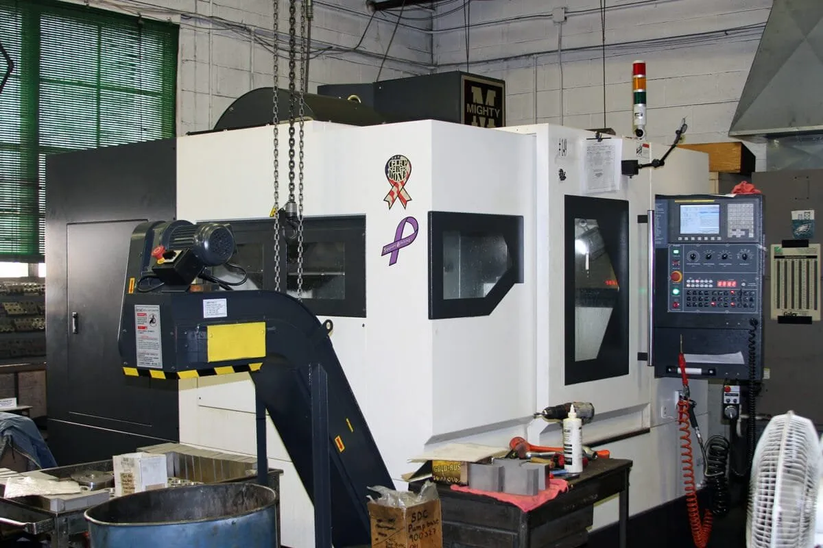 CNC machining center with its control panel and chip conveyor on a machine shop floor — cover image for the Tri-Kris Company website project